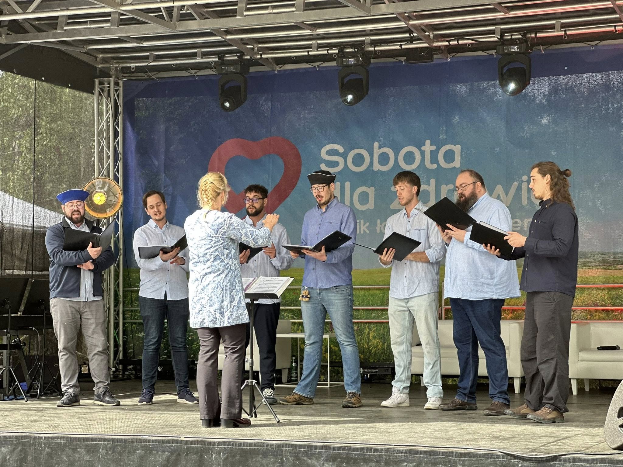 Plenerowy koncert kameralny w parku. Muzycy stoją pod namiotem